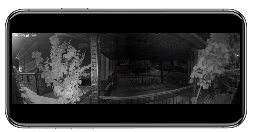 Akıllı telefon ekranında, her iki tarafında bitkilerin göründüğü, kapalı bir veranda ve korkuluğun gece vakti güvenlik kamerası görüntüsü.